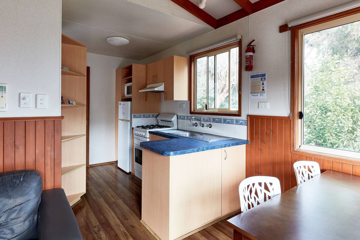Una cocina compacta con armarios de madera, una estufa y una ventana.