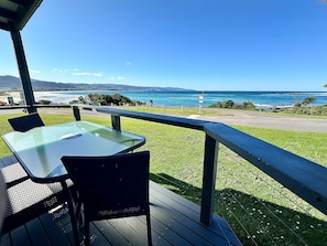 Une terrasse avec une table et des chaises offrant une vue sur la côte.