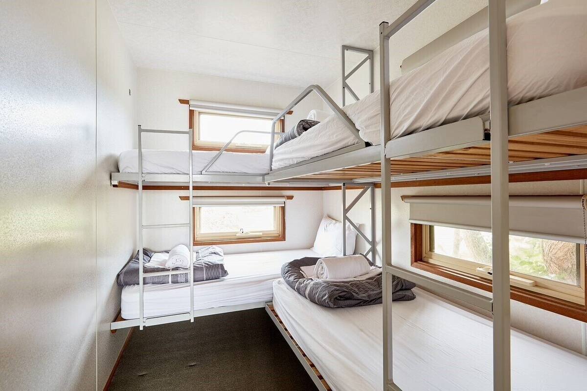 Un dormitorio con literas, una ventana y un pequeño rincón de descanso.