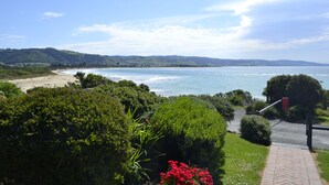 Paisaje costero con playa, vegetación y cielo despejado.