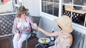 Two people seated at a table with a bottle of wine and a plate of food. - Clearwater Motel Apartments (Esperance)