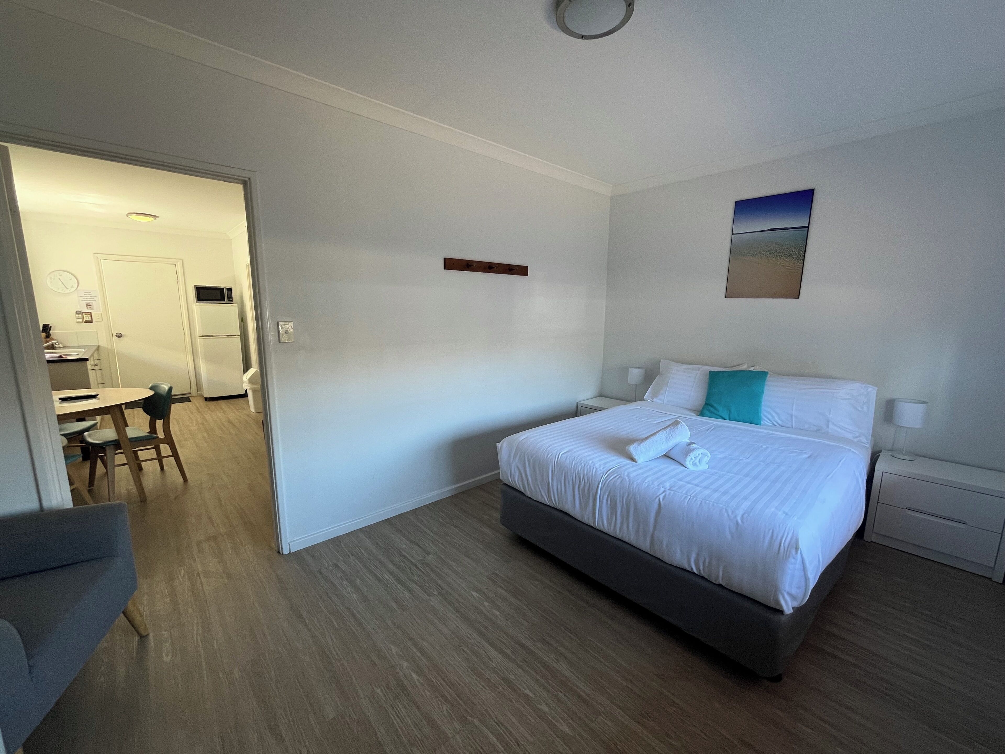 Et hotelværelse med seng, skrivebord og tekøkken.