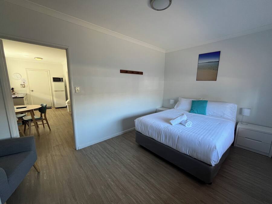 A hotel room with a bed, a desk, and a kitchenette.