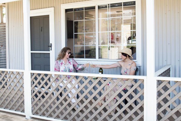 A covered porch with a lattice railing, a white door, and a window with a grid pattern. - Clearwater Motel Apartments (Esperance)