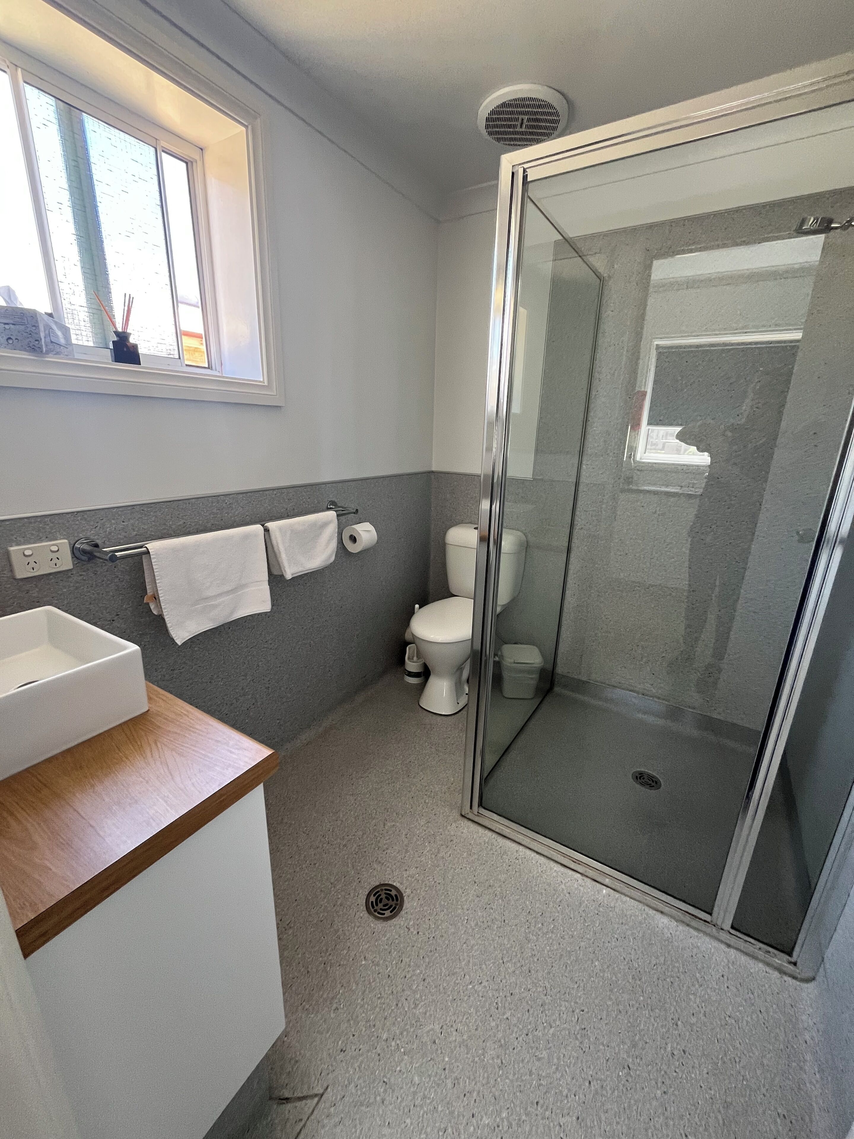 A modern bathroom with a glass shower enclosure, a white sink, and a toilet.