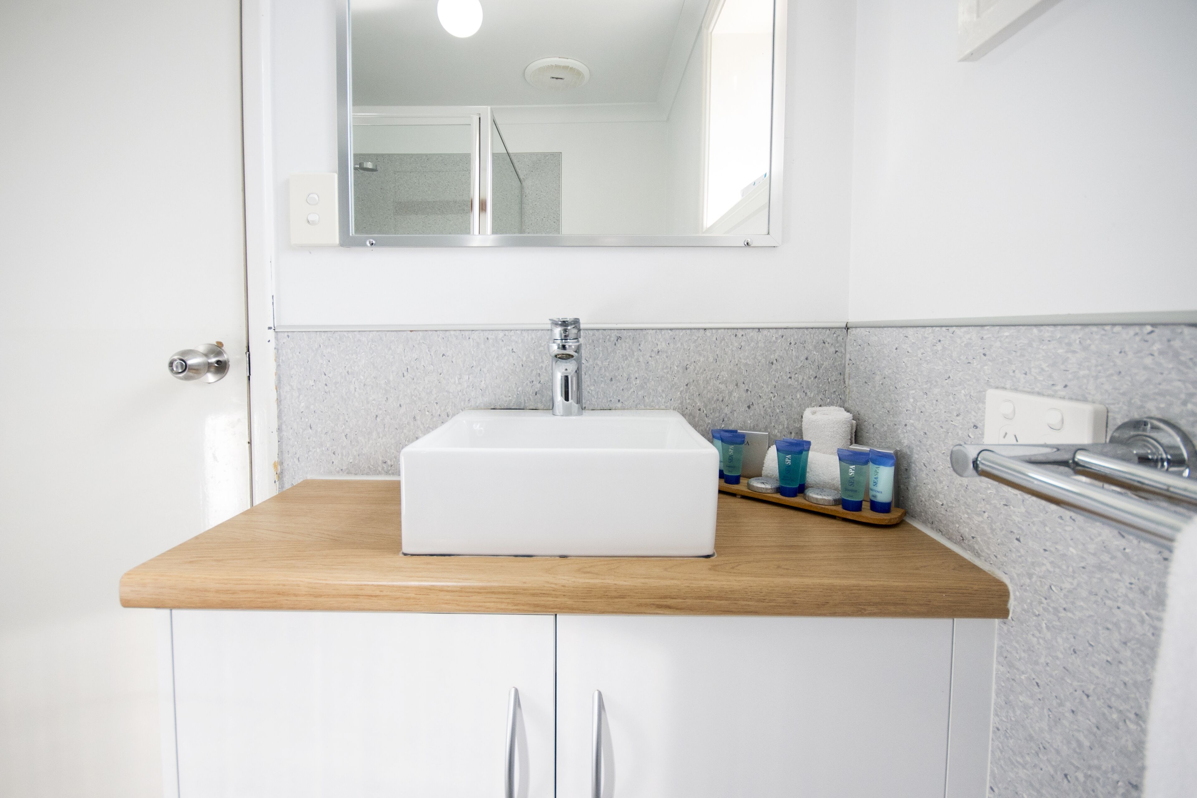 Un baño con un lavabo blanco, encimera de madera y un espejo encima.