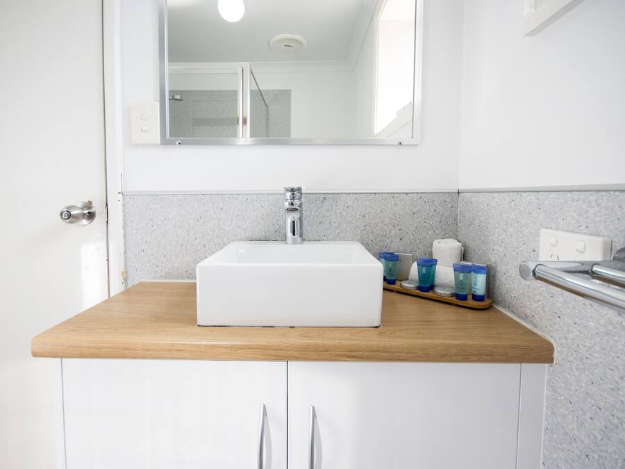 Un baño con un lavabo blanco, encimera de madera y un espejo encima.