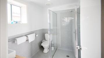 Un baño moderno con ducha de vidrio, inodoro y lavamanos.