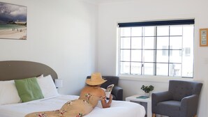 A room with a bed, a reading chair, a window, and a small table with a plant. - Clearwater Motel Apartments (Esperance)