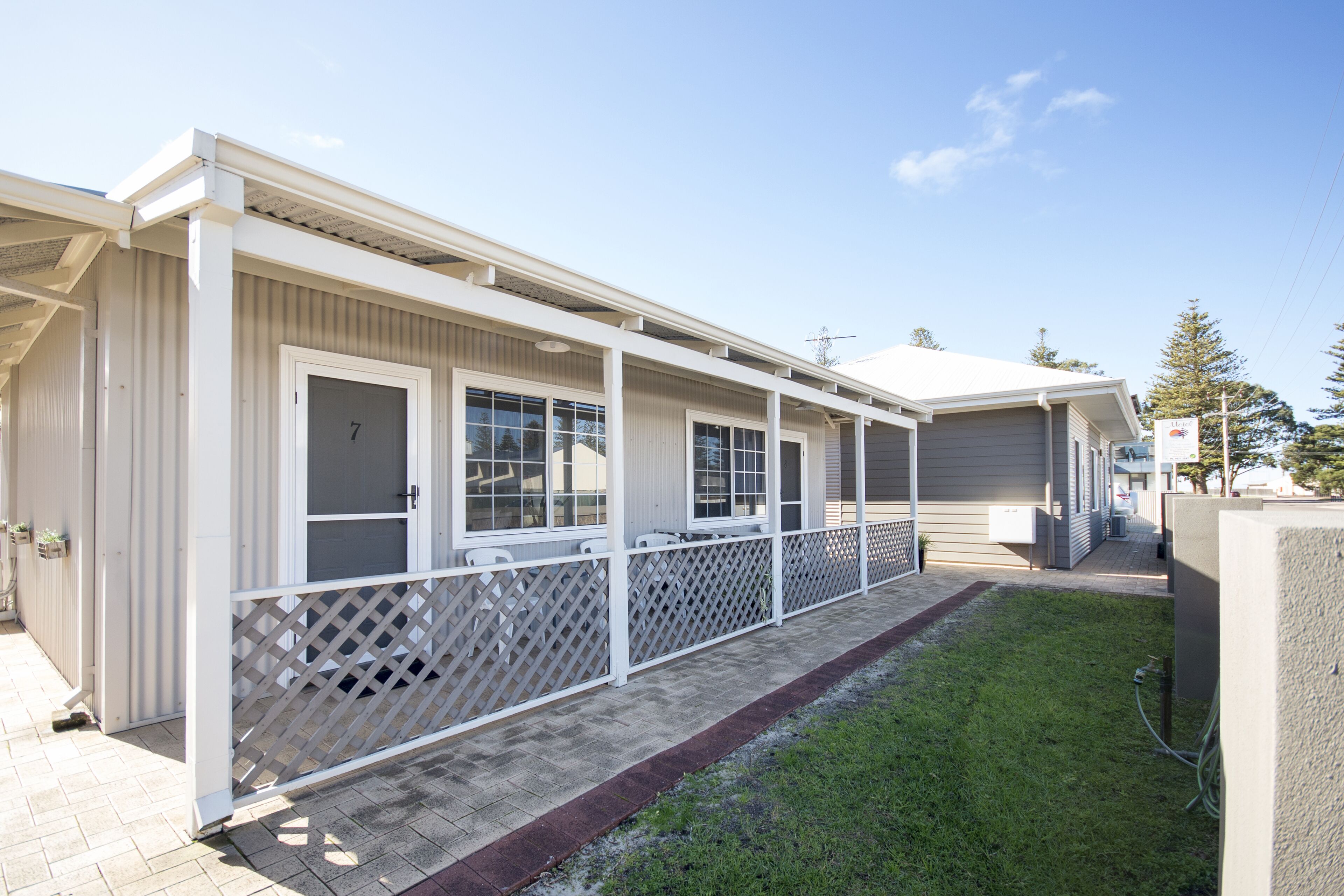 A row of single-story buildings with a covered walkway and a fenced area.
