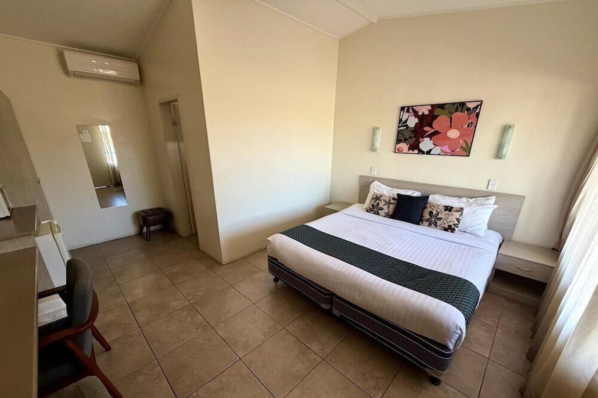 Un dormitorio con cama, una silla, un escritorio y un espejo.