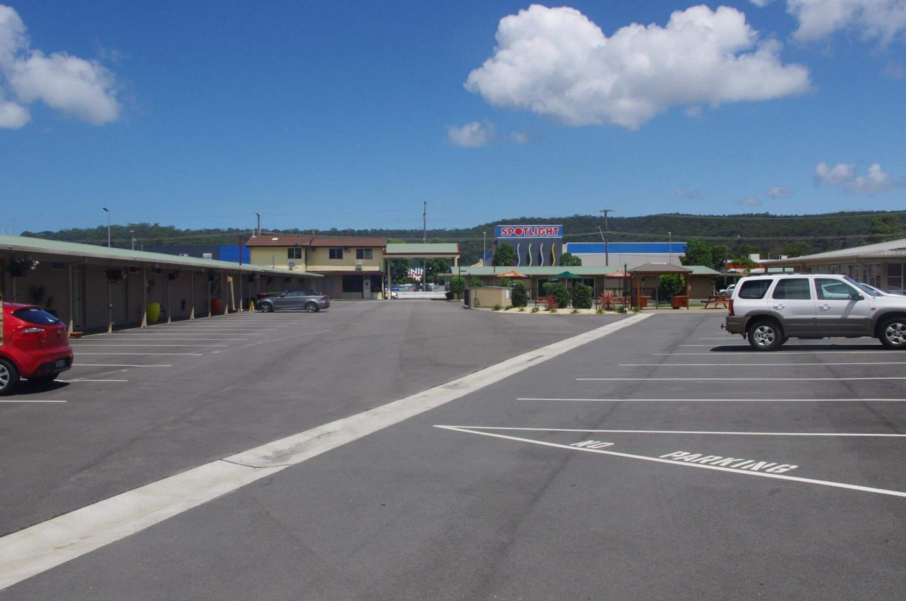 A parking lot with a 'SPOTLIGHT' sign, a row of buildings, and a red car parked on the left.