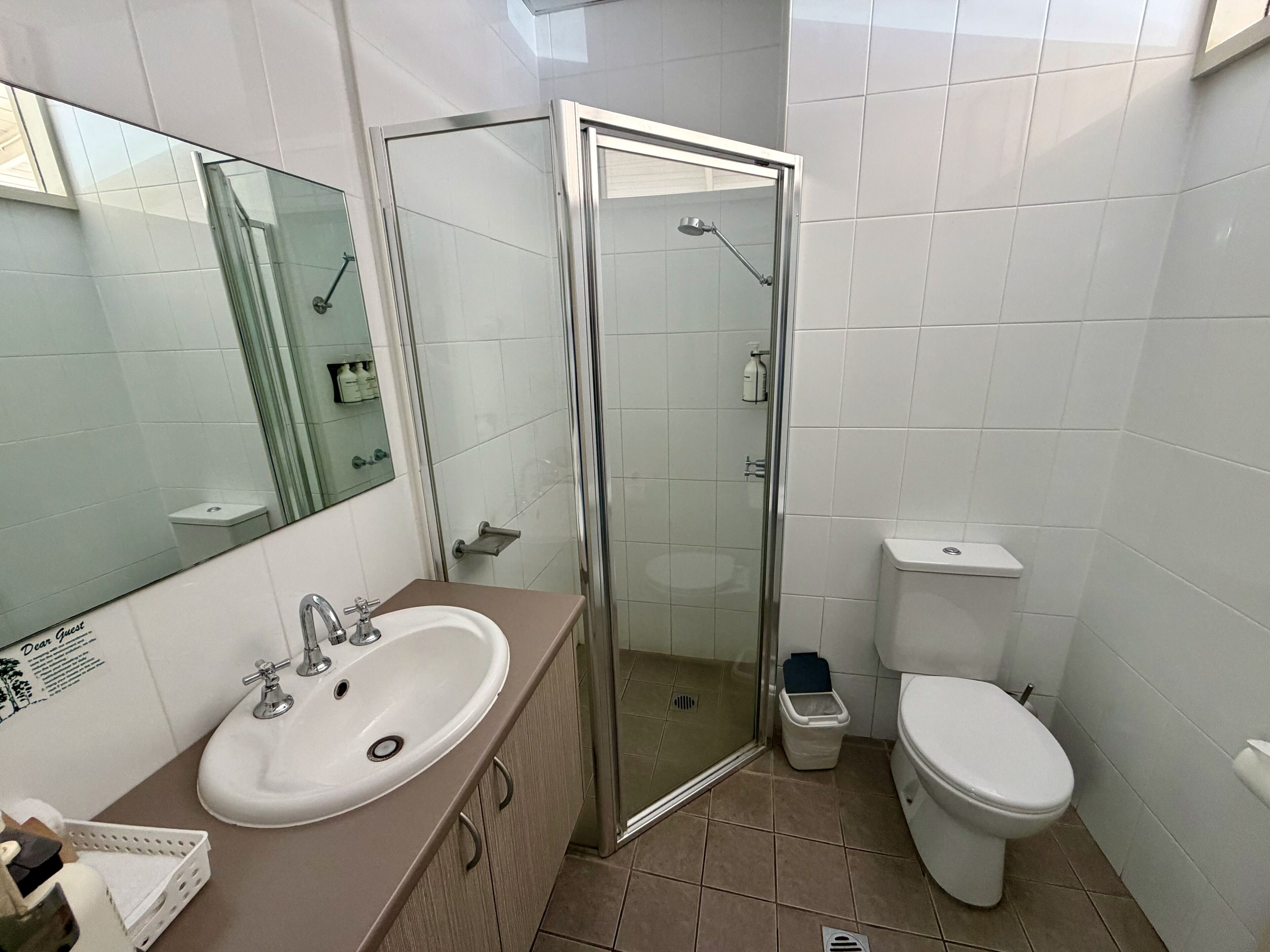 A bathroom with a glass shower enclosure, a white sink, and a toilet.