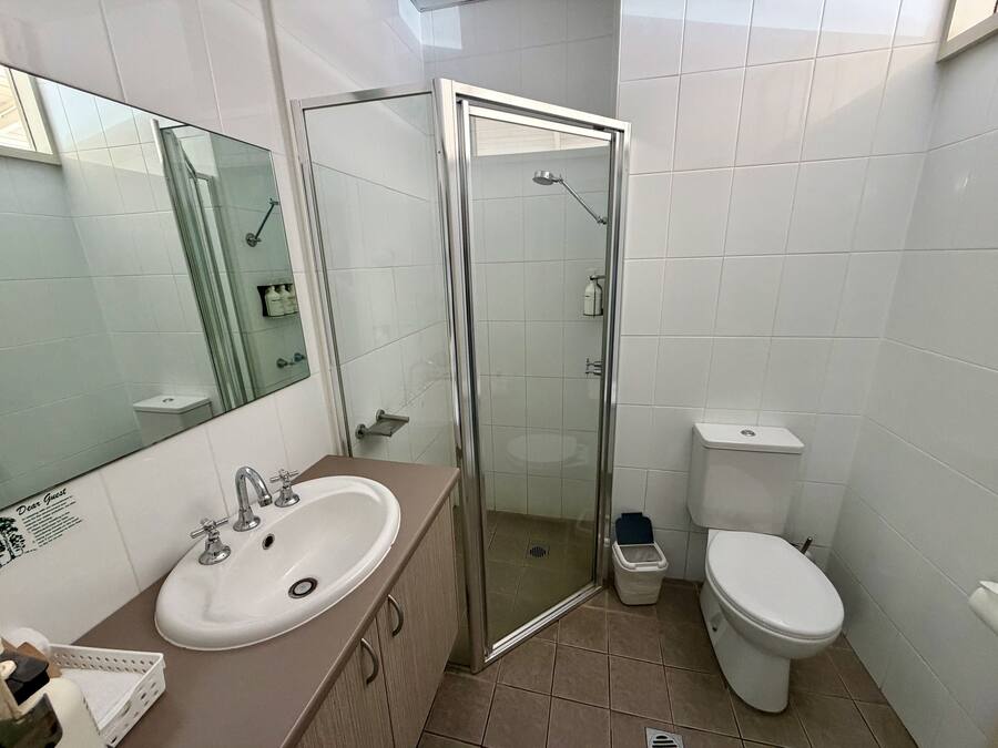 A bathroom with a glass shower enclosure, a white sink, and a toilet.