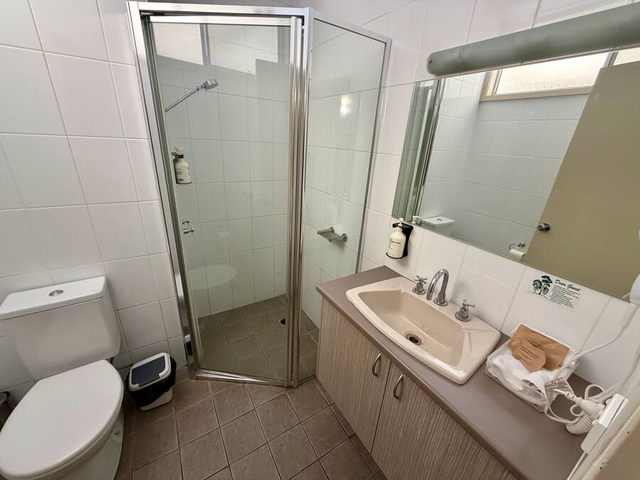 Une salle de bain avec une douche à parois de verre, un lavabo avec un miroir et des toilettes.