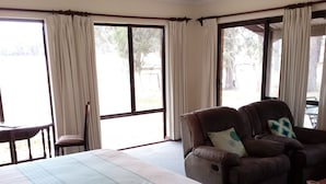 Quarto de hotel com uma cama grande, duas poltronas de couro, uma cadeira de madeira e uma pequena mesa.