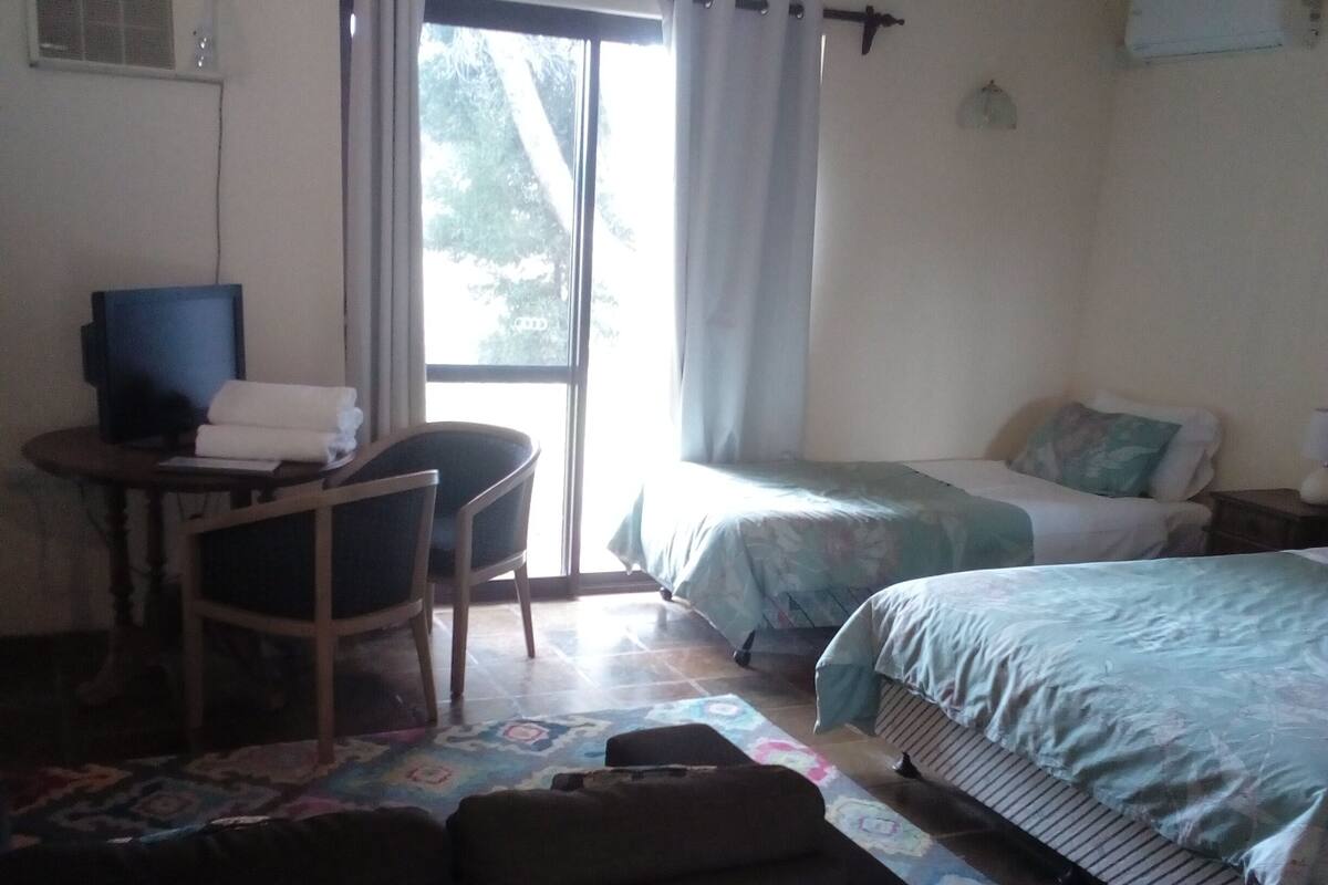 Een kamer met een bed, een bureau met een computer, een stoel en een bank.