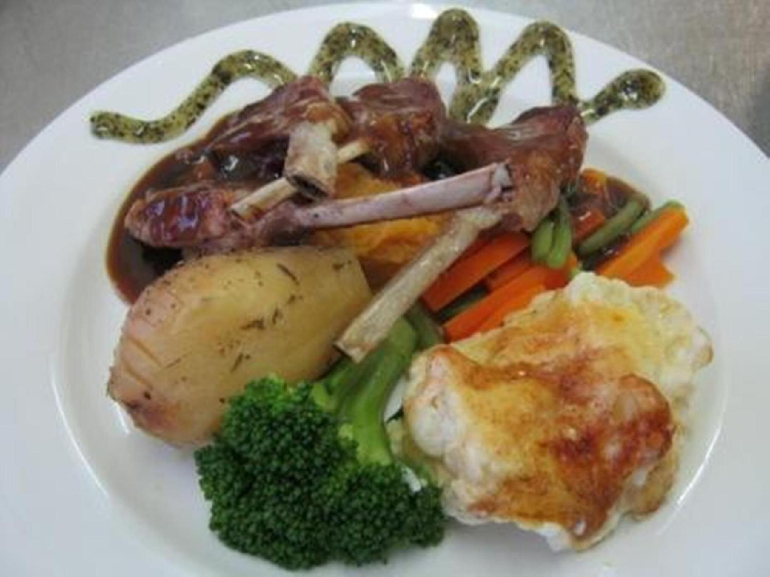 A plate with roasted meat, vegetables, and mashed potatoes.