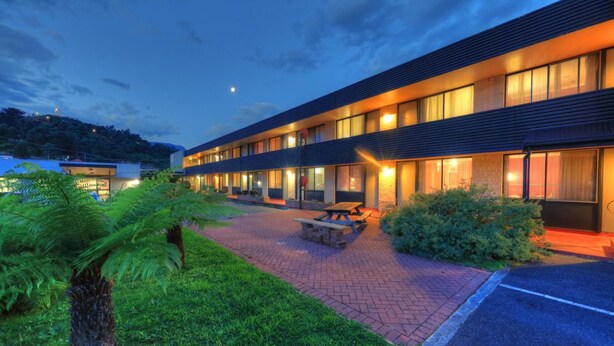 Hotel modern amb teulada plana, finestres grans i un pati pavimentat amb taula de pícnic.