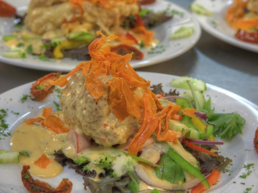 A variety of plated dishes with a focus on a central dish topped with shredded carrots and a creamy sauce.
