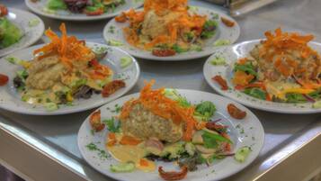 A buffet with plates of food, including meatballs, salad, and vegetables.