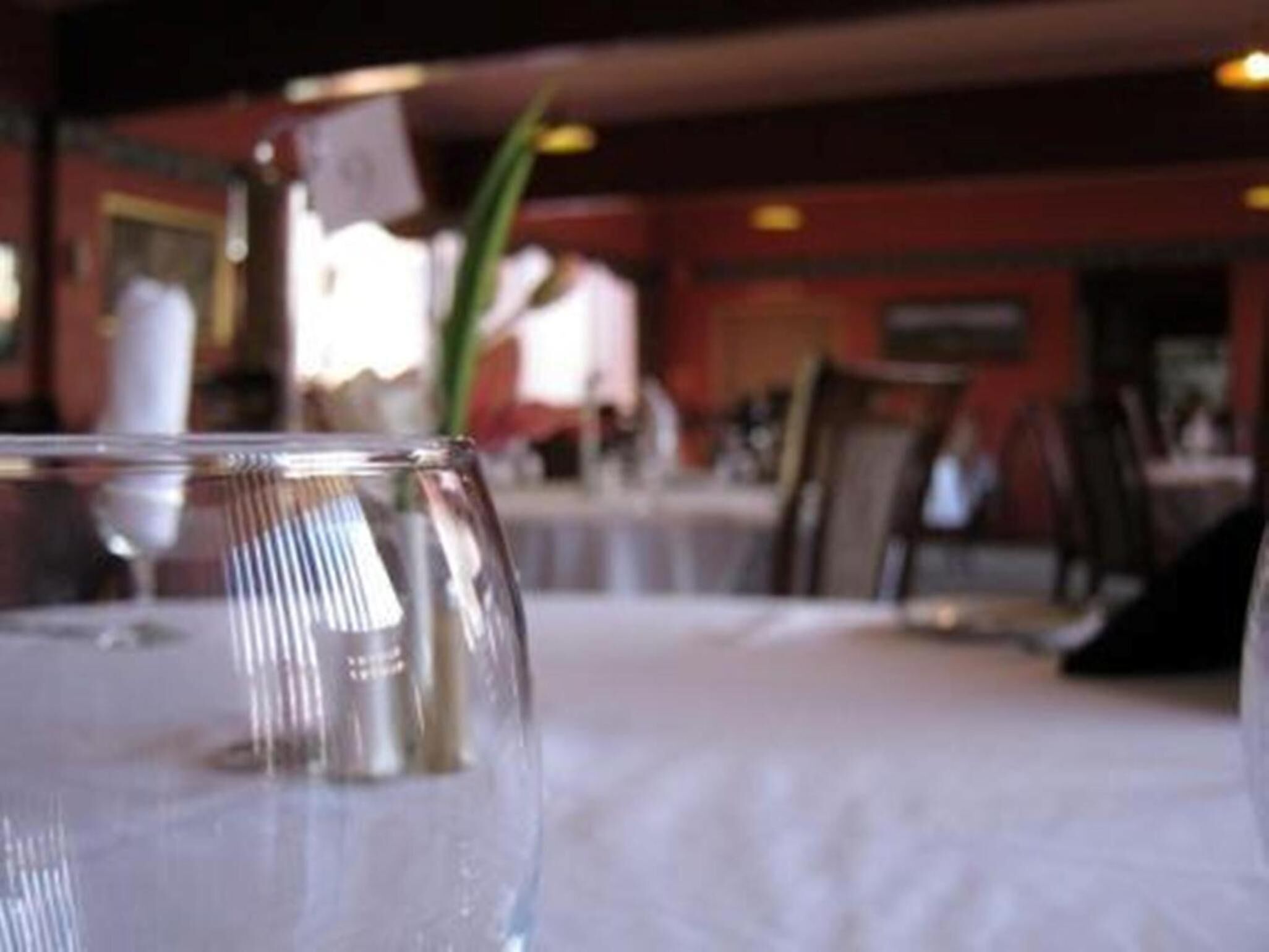 Une table à manger avec un plateau en verre transparent et un chandelier en métal.