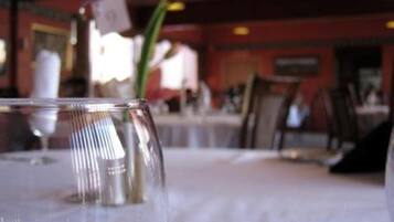 Une table à manger avec un plateau en verre transparent et un chandelier en métal.