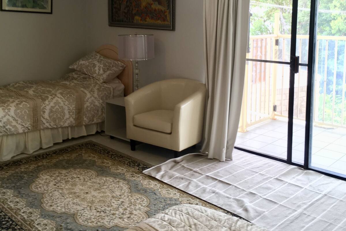 A bedroom with a bed, a chair, a lamp, and a painting on the wall.