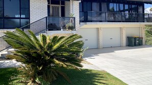 A modern two-story house with a balcony, large windows, and a garage. - Seaview Bed and Breakfast (Bonny Hills)