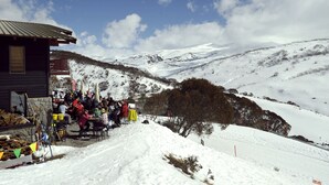 Zona d'estar a l'exterior coberta de neu amb una muntanya de fons.