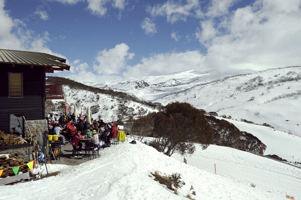 Uma área de estar externa coberta de neve com montanhas ao fundo.