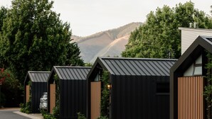 A row of modern, black-roofed cabins with wooden accents, set against a backdrop of lush greenery and mountains. - Big4 Tasman Holiday Parks - Bright (Bright)