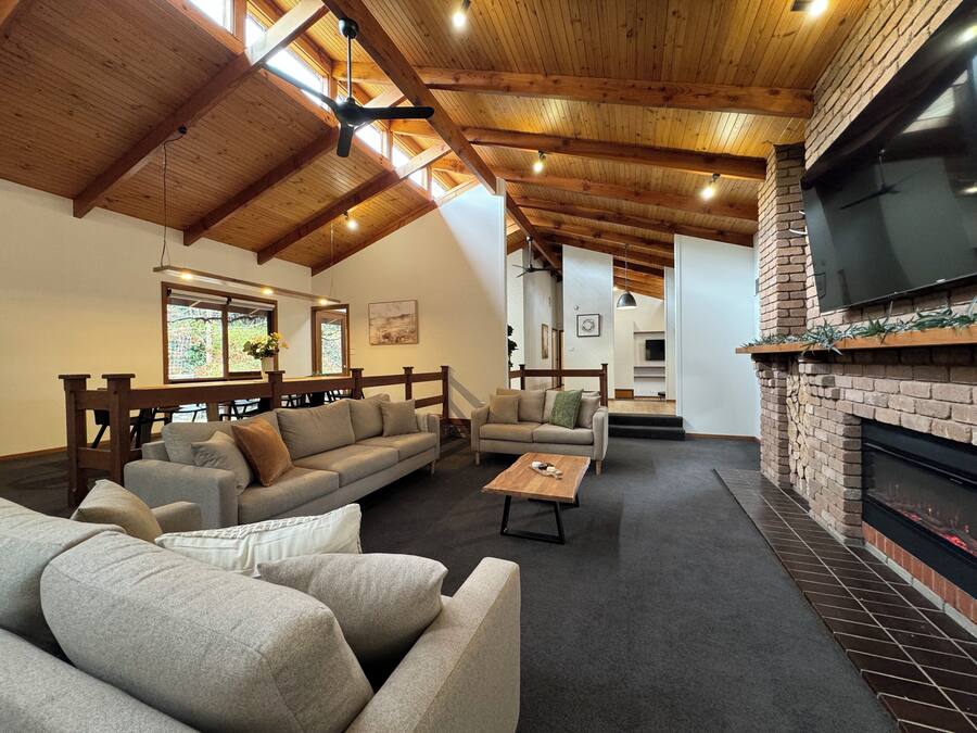 Una sala de estar acogedora con techo de madera alto, una chimenea y una zona de estar cómoda.