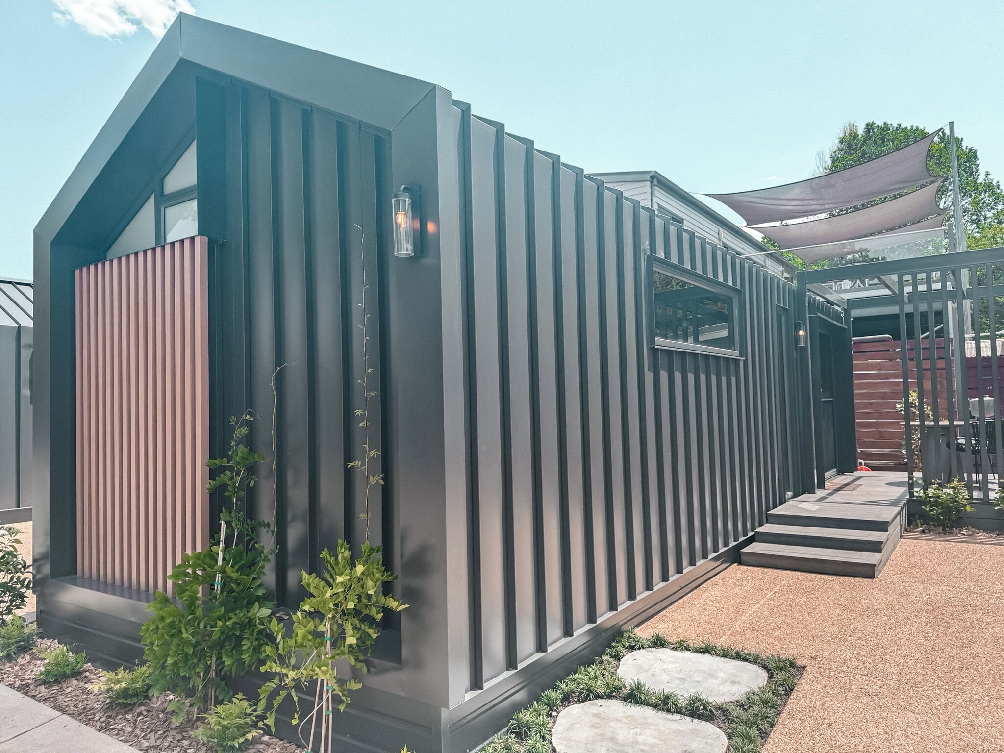 A modern, single-story building with a sloped roof, a vertical wooden panel on the left side, and a small window.