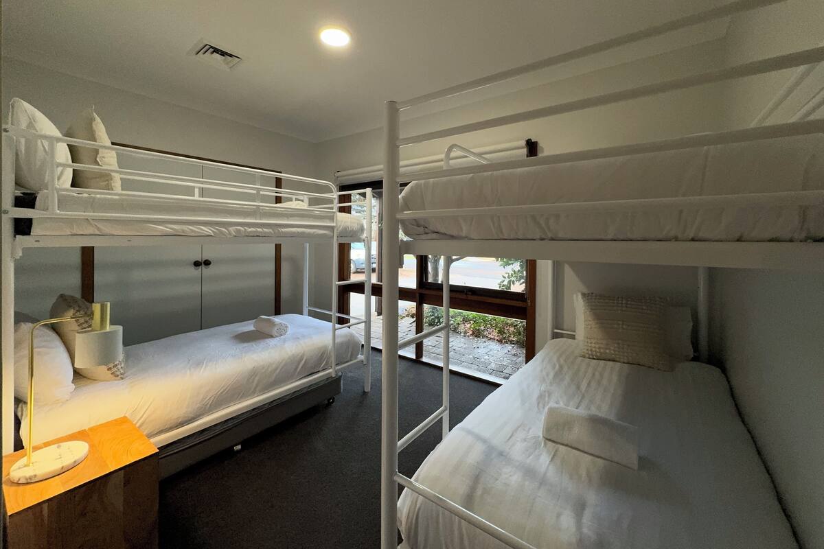 A bunk bed room with a desk and a window.