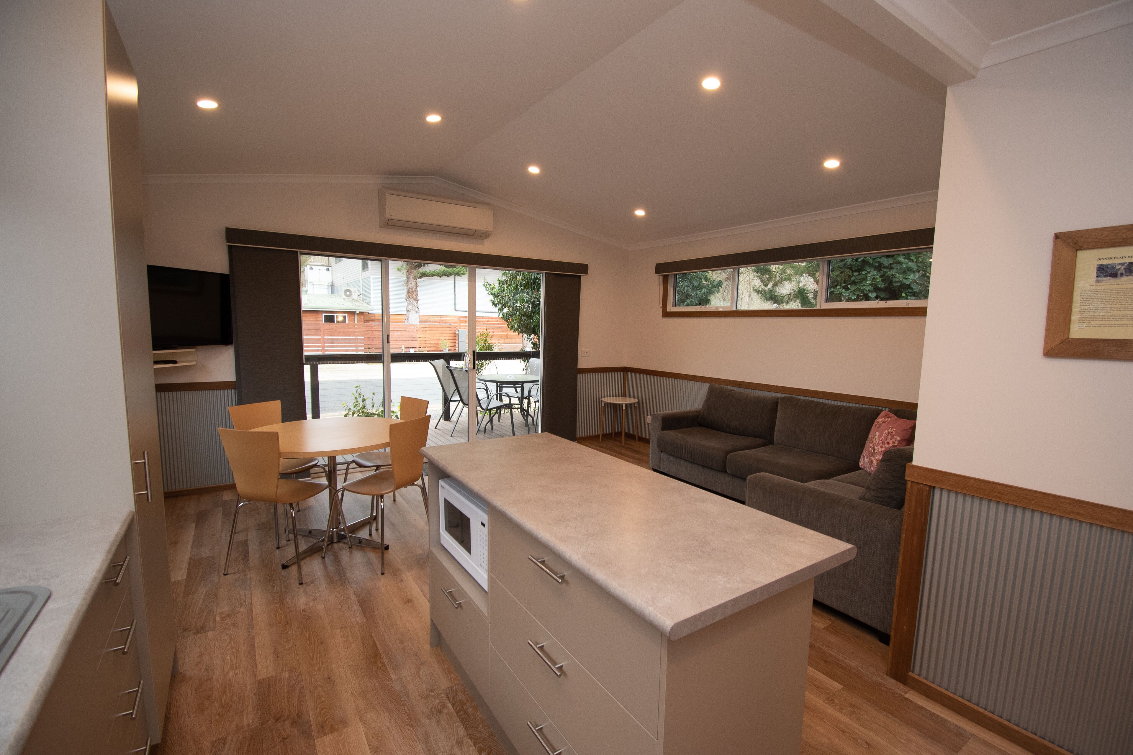 A modern kitchen with a central island, dining area with chairs, and a sofa.