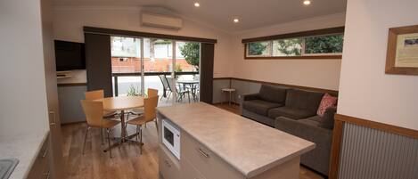 A modern kitchen with a central island, dining area with chairs, and a sofa.