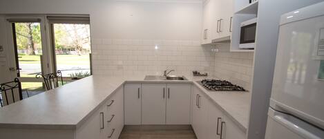 A modern kitchen with white cabinets, a stainless steel sink, a microwave, and a refrigerator.