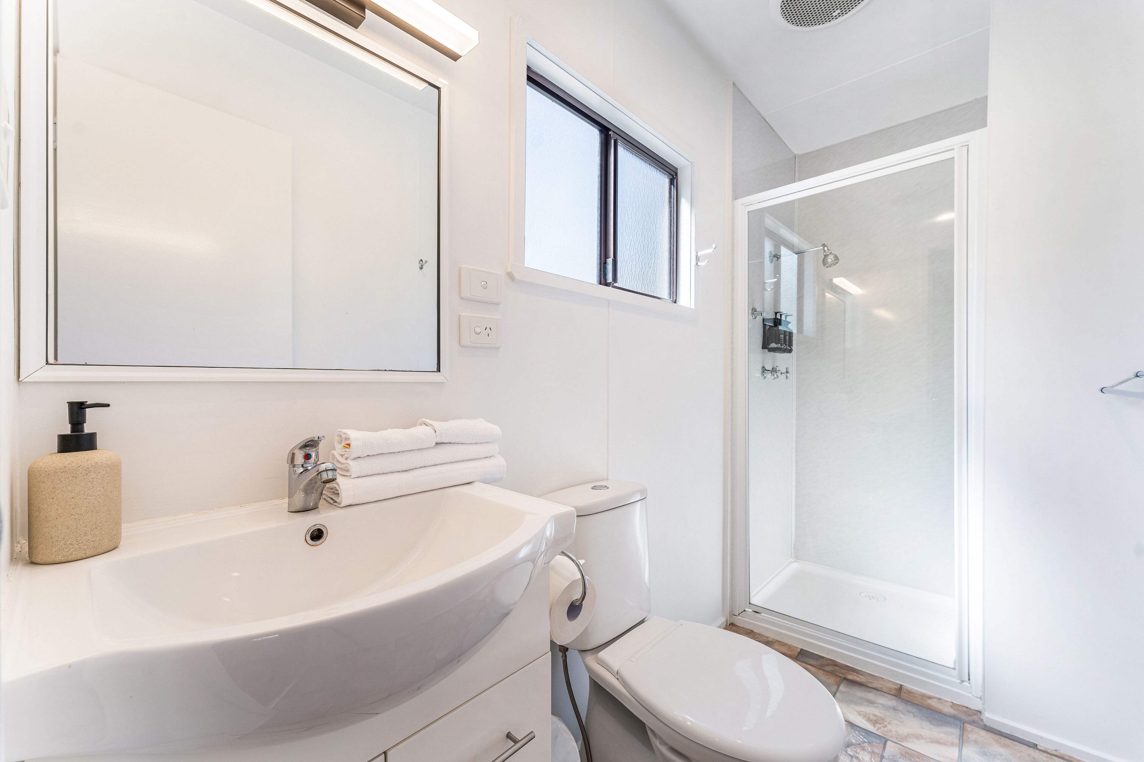 A modern bathroom with a large sink, toilet, and a glass-enclosed shower.