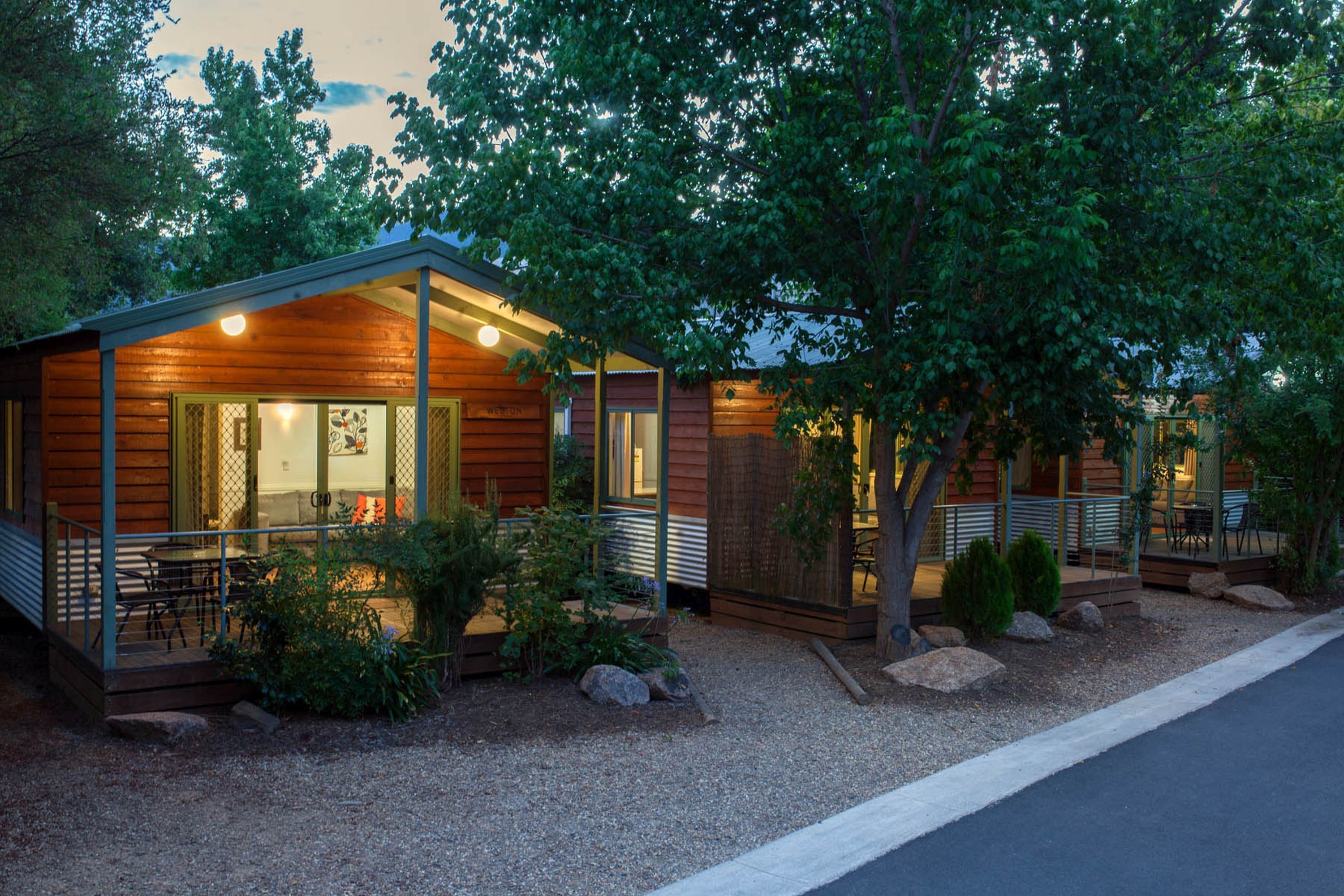 A rustic cabin-style hotel with a covered outdoor seating area and a well-maintained garden.