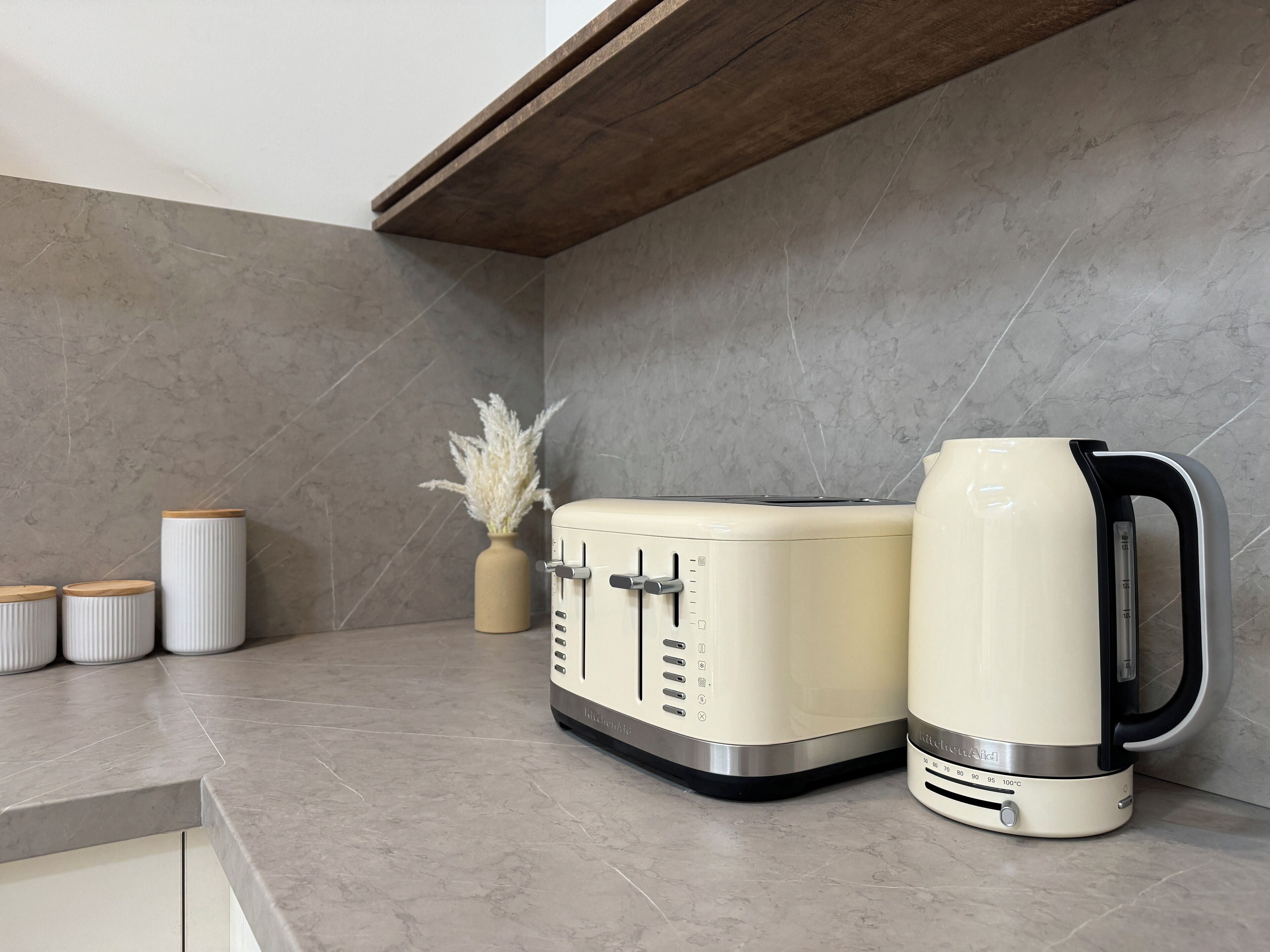 A kitchen with a modern design, featuring a built-in oven and a kettle on the countertop.