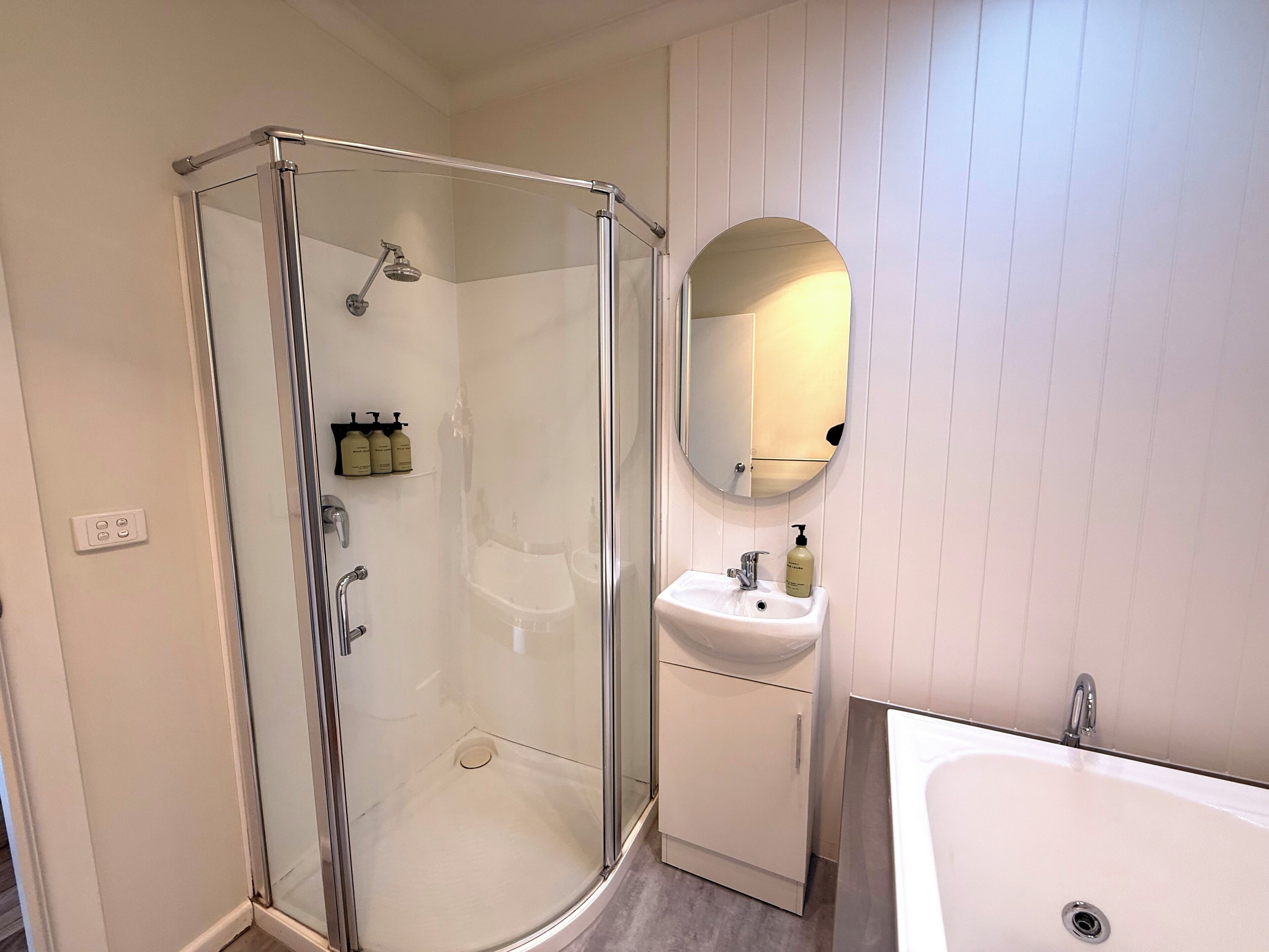 Un baño moderno con ducha acristalada, lavamanos y espejo.