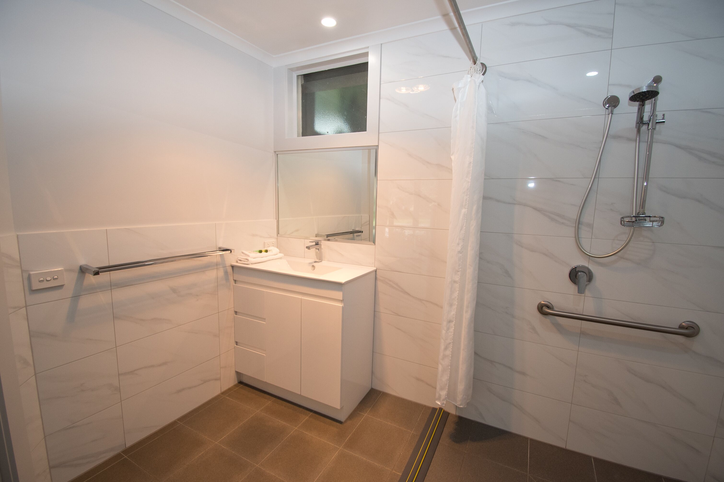Un baño moderno con ducha, lavabo y espejo.
