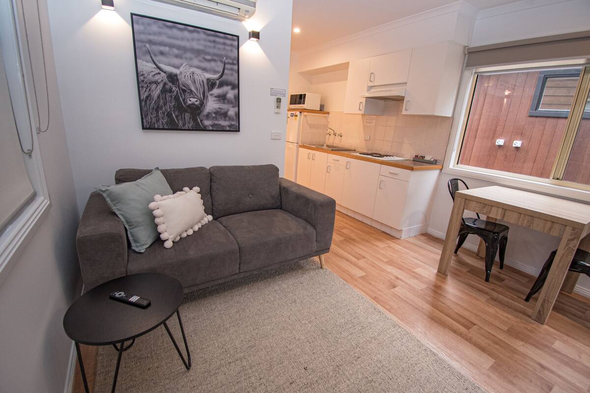 A living room with a sofa, a small table, and a remote control on the table.