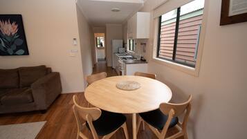 A dining area with a round table and chairs, a sofa, and a kitchen in the background.