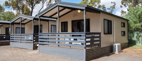 A caravan with a covered porch and a fenced area.