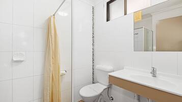A bathroom with a toilet, sink, and shower.