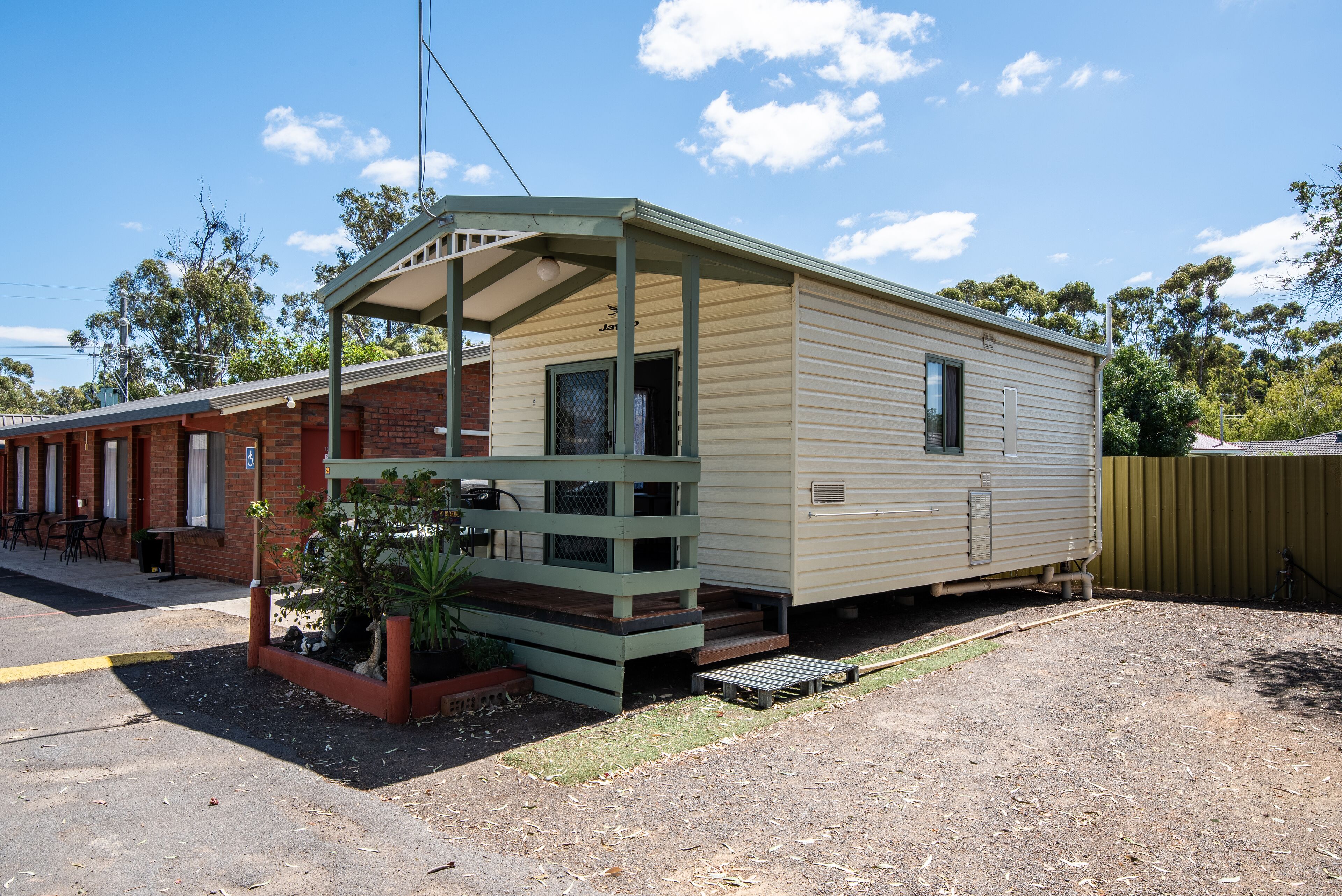 A mobile home with a porch and a small garden area.