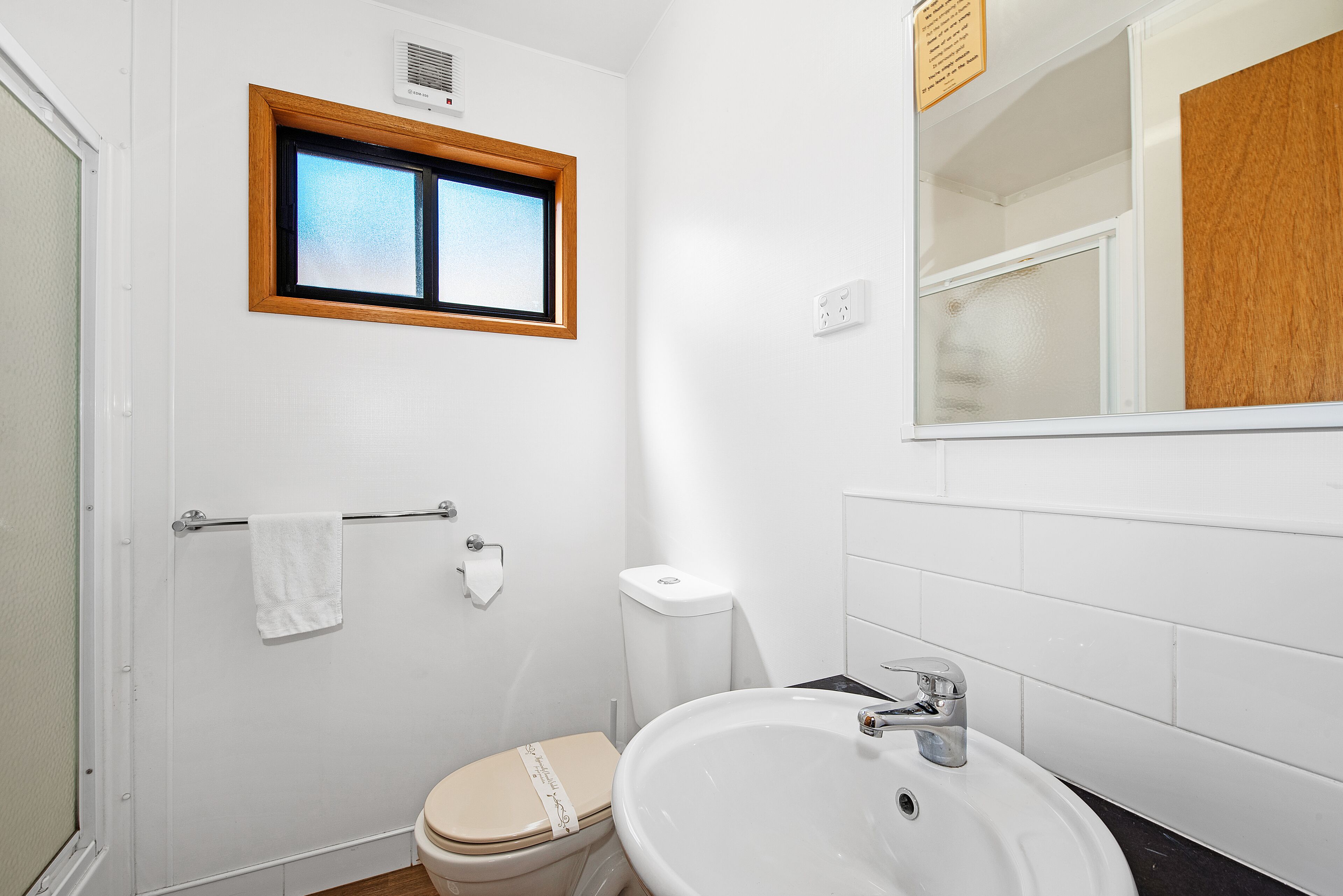 Ein kleines, sauberes Badezimmer mit Toilette, Waschbecken und Fenster.