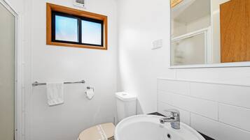 Ein kleines, sauberes Badezimmer mit Toilette, Waschbecken und Fenster.